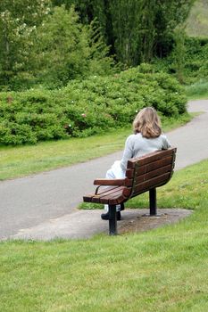 Female relaxing on park bench outside.