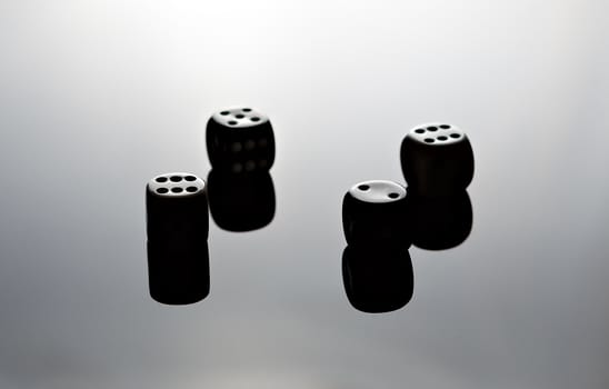 Four dice reflecting on black surface.
