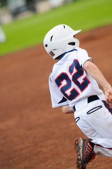 Little league baseball player running to first base.