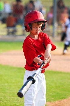 Baseball boy looking down while warming up to bat.