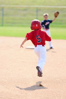 Little league boy running to second base.
