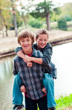 Portrait of Two cute young brothers riding piggy back outdoors