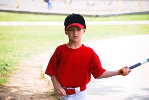 Youth baseball boy holding bat looking at camera.