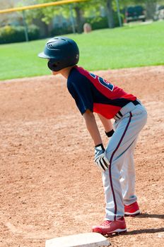 Teen baseball player waiting on first base.