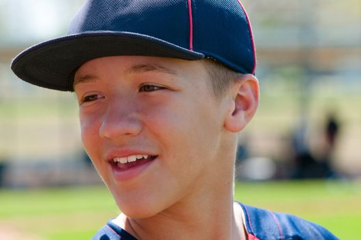 Teen baseball player up close and smiling.