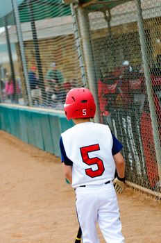 Little league baseball batter walking out to base.