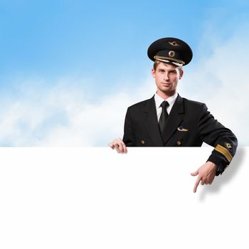 pilot in the form of holding an empty billboard on the background of sky with clouds, place for text