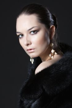 The portrait of woman in fur coat on black background