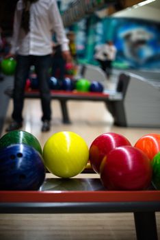 Bowling scene: Colorful balls in the foreground and casual man picking bis ball in the background