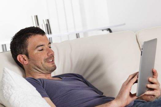man using tablet pc on sofa at home