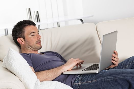 man using computer on sofa at home