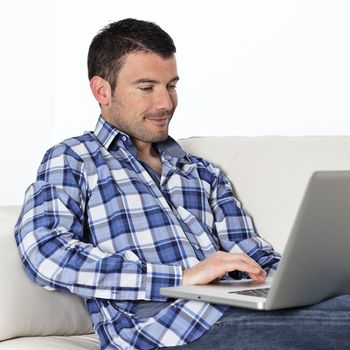 relaxed man sitting on sofa with computer