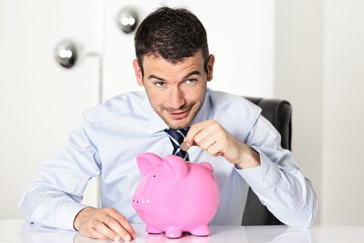 man with coin and pink piggy bank