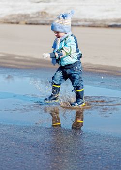 little boy goes on a pool in rubber boots