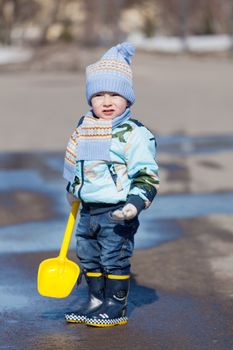 little boy with a toy yellow shovel costs in a pool