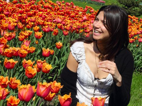 Laughing young woman on spring tulips background