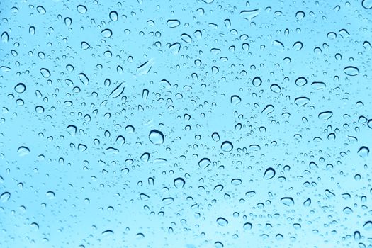 Water drops on blue transparent glass close up
