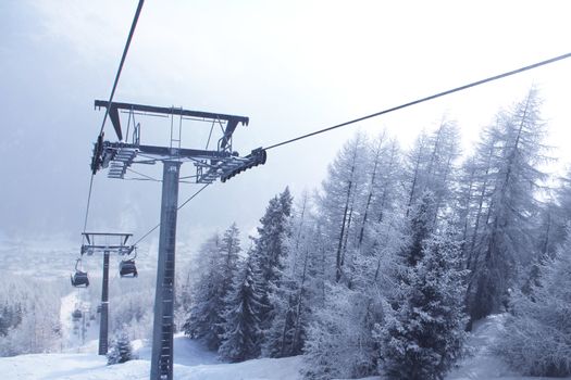 Chair lift between beautiful firs in winter mountains forest