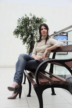 Young beautiful brunette woman sitting on bench