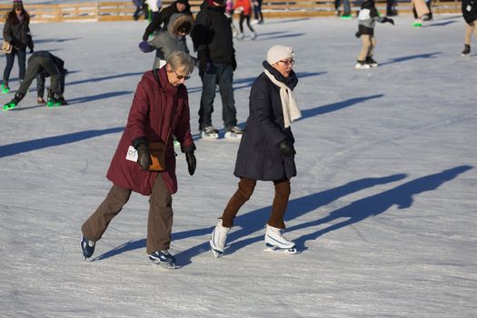 Two elder women are enjoying their lives by ice skating in the beautiful Skating Rink in Old Port of Montreal, Quebec ,Canada