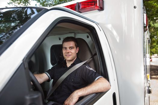 Portrait of a male paramedic sitting in driver seat of white ambulance