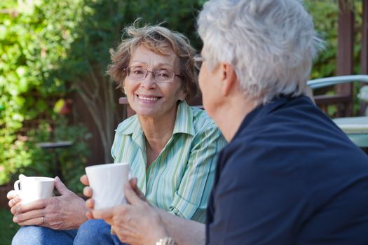 Two senior women enjoying a warm drink outdoors