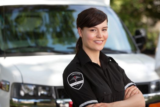 Portrait of a happy friendly female paramedic standing in front of ambulance