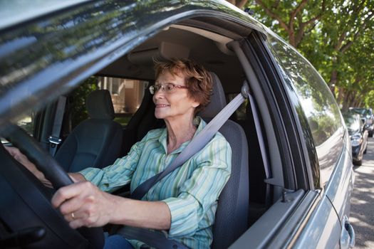 Active senior woman smiling while driving car