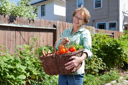 Smiling senior woman holding basket filled with vegetables