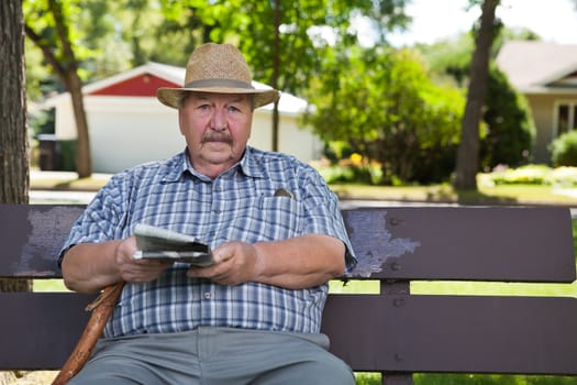 Portrait of senior man holding newspaper in park