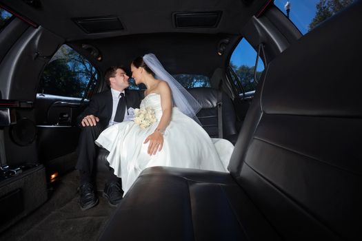 Loving newlywed bride and bridegroom in car