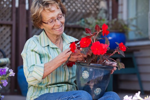 Cheerful senior woman looking at flower pot