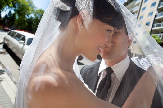 Happy newly wed couple standing together with limo in background