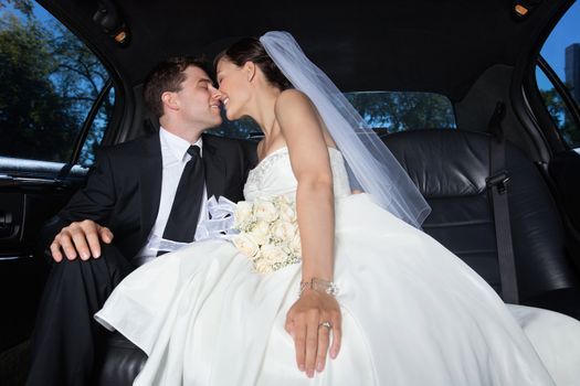 Loving newlywed bride and groom in limousine