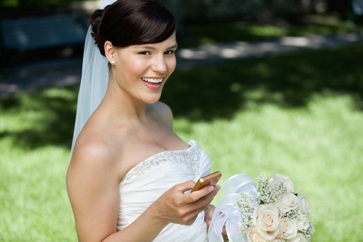 Portrait of happy bride holding cell phone