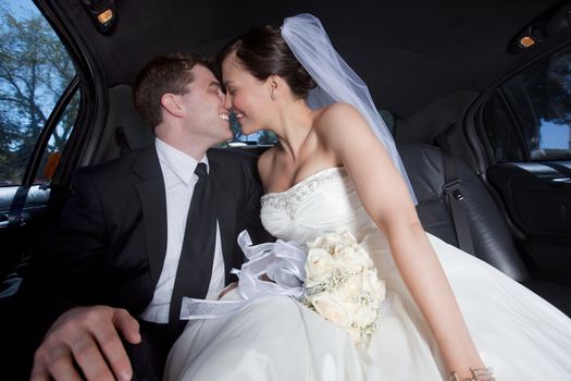 Newlywed couple kissing inside a luxurious limousine