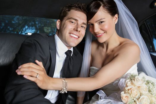 Portrait of newlywed couple smiling sitting in limousine