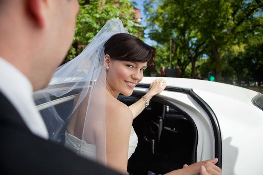 Portrait of beautiful bride getting in limousine