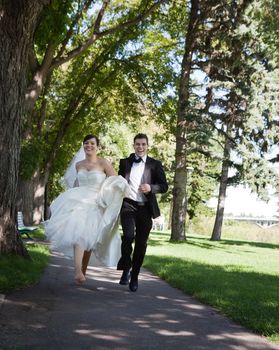 Happy bride and groom running along the walkway