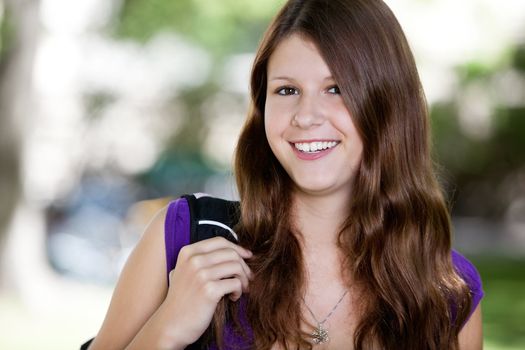 Close-up portrait of a cute teenage girl holding backpack