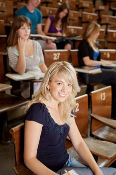 Pretty blond student in lecture theater looking at camera