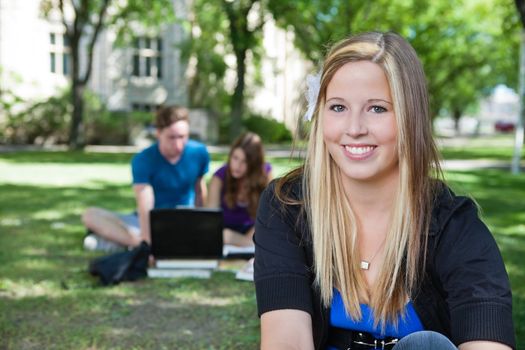 Portrait of happy teenage girl with classmates in background