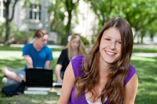 Portrait of happy teenage girl with classmates in background