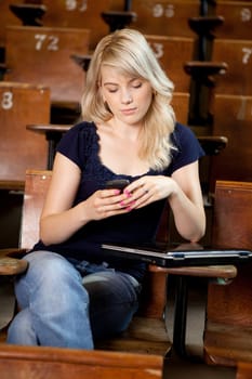 College girl writing an sms while sitting in a lecture hall