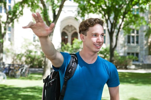 Young college student waving his hand