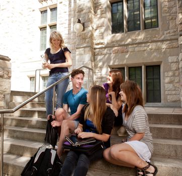 Group of university or college students sitting on steps, visiting and having fun