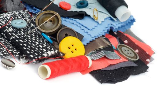 Sewing Items with Various Buttons, Pins, Spools, Red Threads and Textile closeup on white background