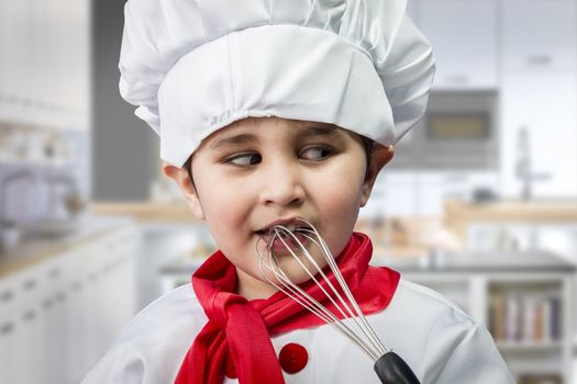 Funny boy dressed in chef, cooking in a kitchen