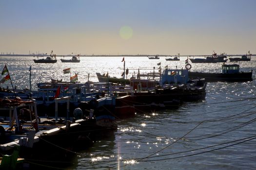 Dwarka Roadtrip. Landscape of Bet Dwarka harbor. Sunlight reflections on the ripples of the waves broken by moored fishing boats and passenger ferries in Gujarat India