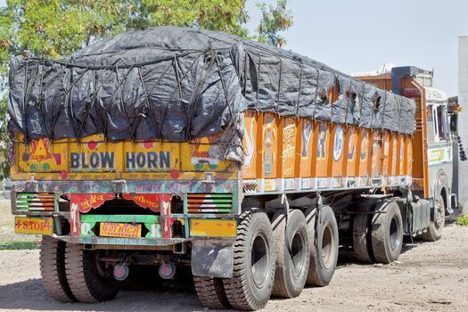 Colorful Indian heavy goods vehicle parked up at  Dhabha (Indian truck stop) in the mid day sun while the driver and crew take an after noon nap from the heat of the Indian sun.